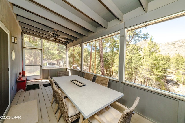 sunroom / solarium featuring a ceiling fan, outdoor dining area, a wealth of natural light, and beamed ceiling