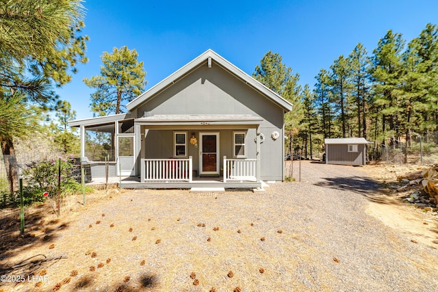 bungalow-style home with a storage shed, an outdoor structure, and a porch