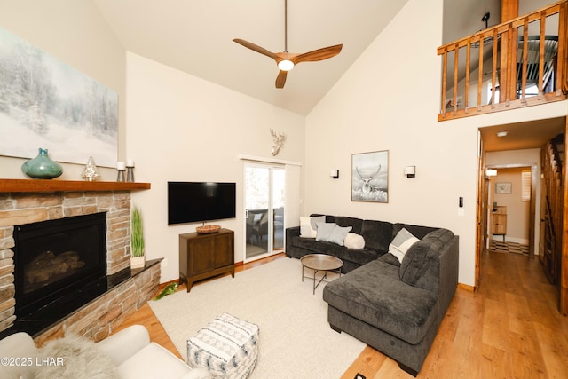 living area with a ceiling fan, high vaulted ceiling, wood finished floors, and a fireplace