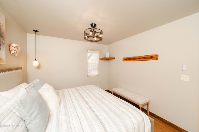 bedroom with an inviting chandelier, baseboards, and light wood-style flooring