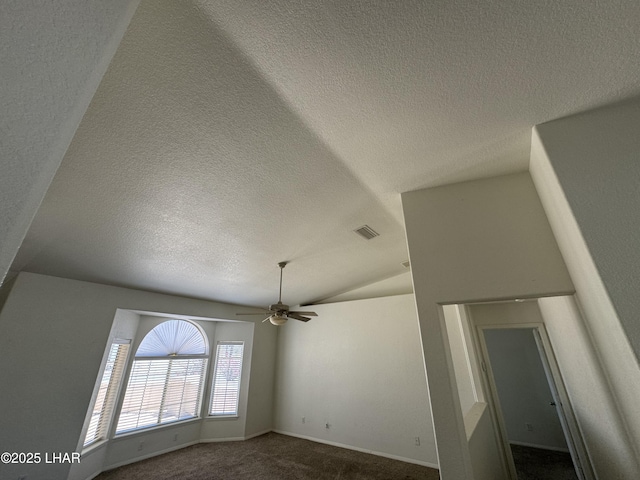 unfurnished room featuring ceiling fan, lofted ceiling, dark carpet, and a textured ceiling