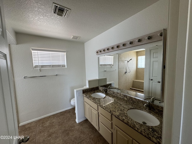 bathroom featuring tile patterned flooring, vanity, a textured ceiling, and toilet