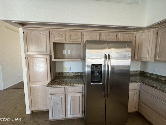 kitchen with stainless steel fridge, light brown cabinetry, and dark tile patterned flooring