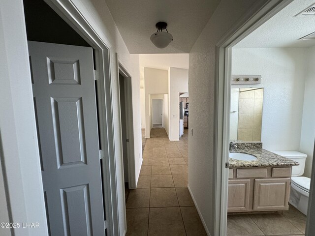 corridor with light tile patterned flooring and sink