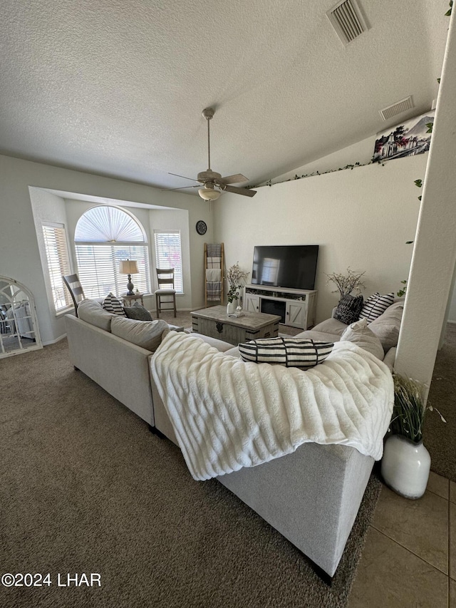 carpeted living room featuring ceiling fan and a textured ceiling