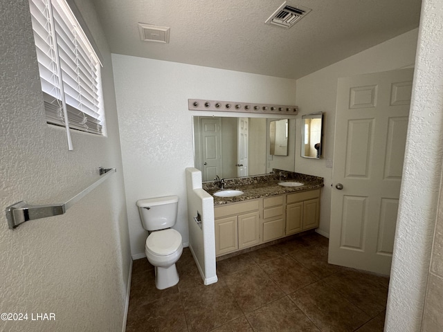 bathroom featuring tile patterned flooring, vanity, a textured ceiling, and toilet