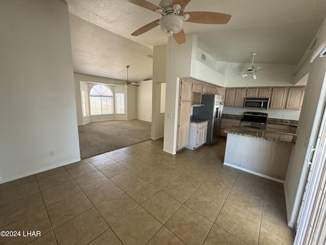 kitchen featuring vaulted ceiling, appliances with stainless steel finishes, light colored carpet, ceiling fan, and a textured ceiling