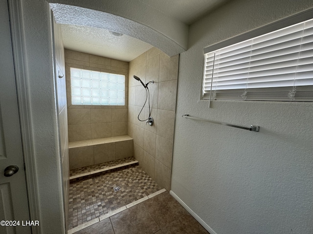 bathroom with tiled shower, tile patterned flooring, and a textured ceiling