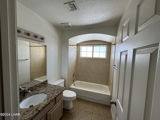 full bathroom with toilet, a textured ceiling, vanity, tiled shower / bath combo, and tile patterned flooring