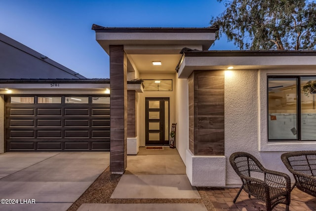 exterior entry at dusk featuring a garage