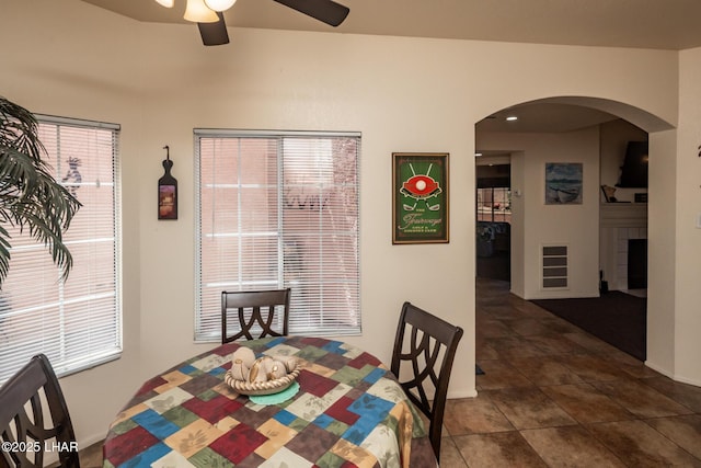 1650 S Smoketree Ave Unit 103, Lake Havasu City, AZ 86403 - dining space featuring ceiling fan, arched walkways, a fireplace, dark tile patterned flooring, and baseboards