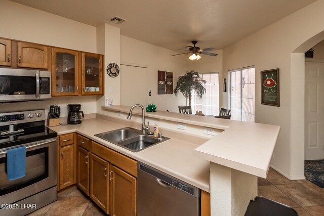 1650 S Smoketree Ave Unit 103, Lake Havasu City, AZ 86403 - kitchen with appliances with stainless steel finishes, a sink, a peninsula, brown cabinetry, and ceiling fan