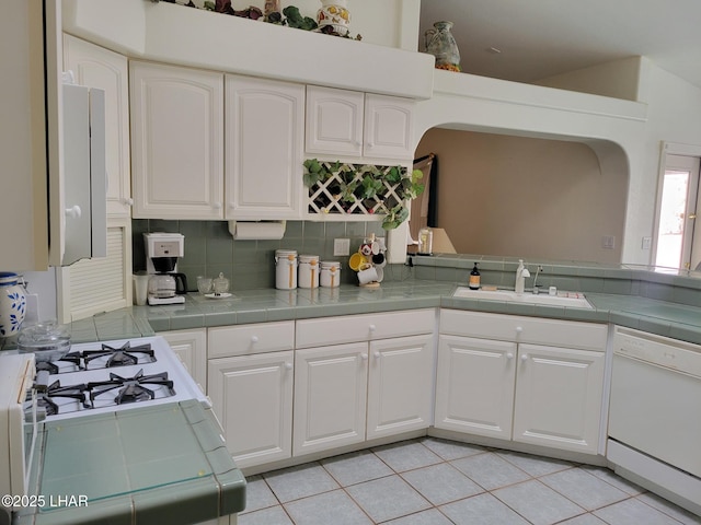 kitchen with white appliances, a sink, tile counters, and white cabinetry