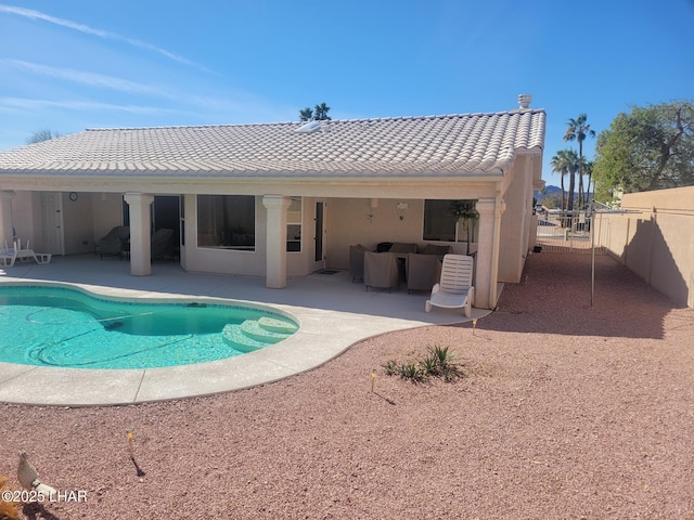 rear view of house with a tile roof, a patio area, fence, and stucco siding