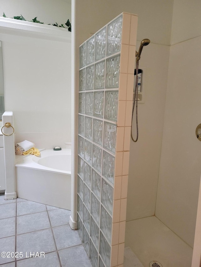 full bathroom featuring a tile shower, a bath, and tile patterned floors