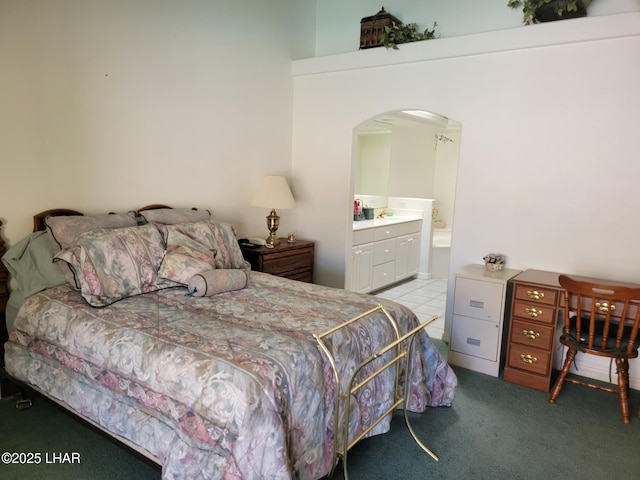 bedroom featuring arched walkways, light carpet, and connected bathroom