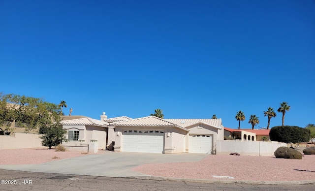 view of front of property featuring a tile roof, stucco siding, an attached garage, fence, and driveway