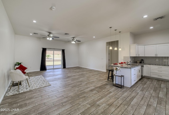2225 E Moon Ridge Ln, Fort Mohave, AZ 86426 - kitchen featuring white cabinets, a breakfast bar area, open floor plan, tasteful backsplash, and recessed lighting