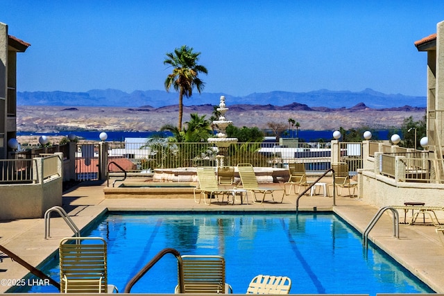 pool featuring a mountain view, fence, and a patio area
