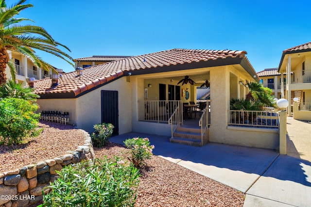 mediterranean / spanish house with a tile roof, stucco siding, and covered porch