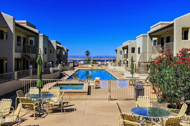 pool with fence, a patio, a mountain view, and a residential view