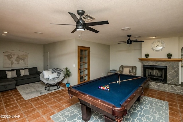 recreation room with visible vents, ceiling fan, a tiled fireplace, and tile patterned floors