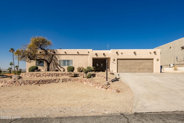 pueblo-style home featuring a garage, driveway, and stucco siding