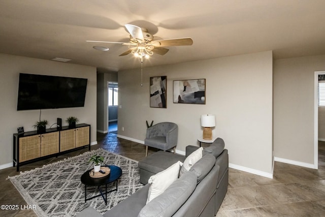 living area featuring a ceiling fan and baseboards