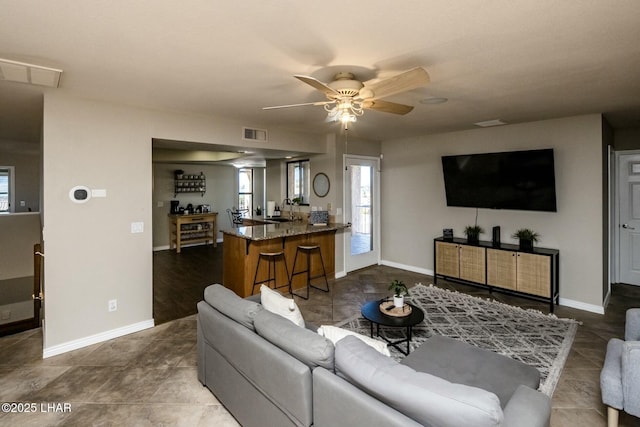 living area featuring ceiling fan, visible vents, and baseboards