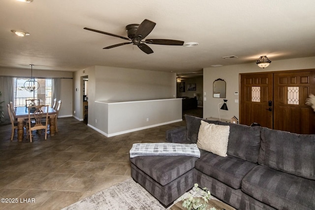 living room featuring ceiling fan with notable chandelier, tile patterned flooring, visible vents, and baseboards