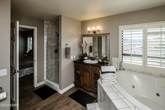 ensuite bathroom with wood finished floors, vanity, baseboards, a jetted tub, and a stall shower