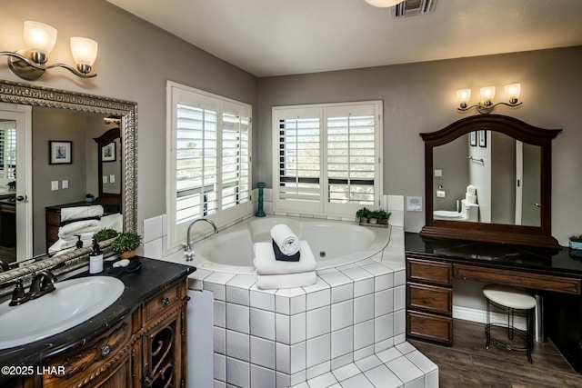 full bath with visible vents, a tub with jets, wood finished floors, and vanity