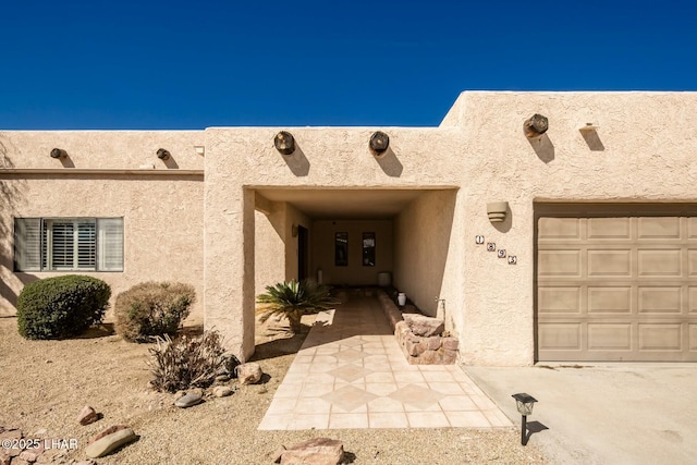 entrance to property featuring a garage and stucco siding