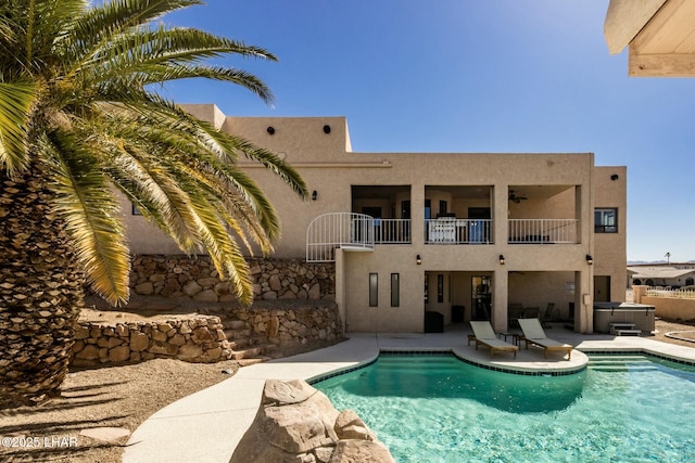 outdoor pool with a patio area and a hot tub