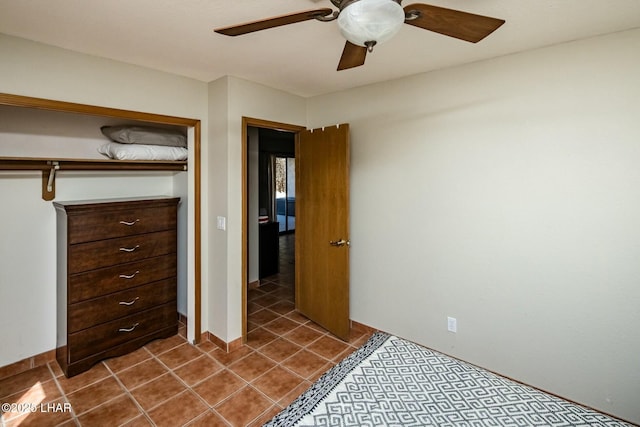 unfurnished bedroom featuring ceiling fan, dark tile patterned floors, and baseboards