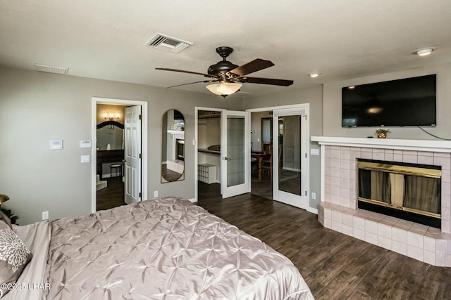 bedroom featuring dark wood-style floors, visible vents, a tiled fireplace, and ensuite bathroom