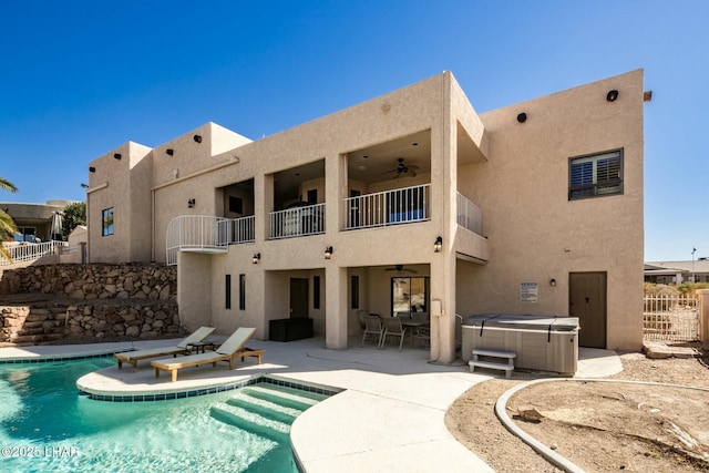 rear view of house featuring a hot tub, a ceiling fan, a balcony, fence, and a patio area