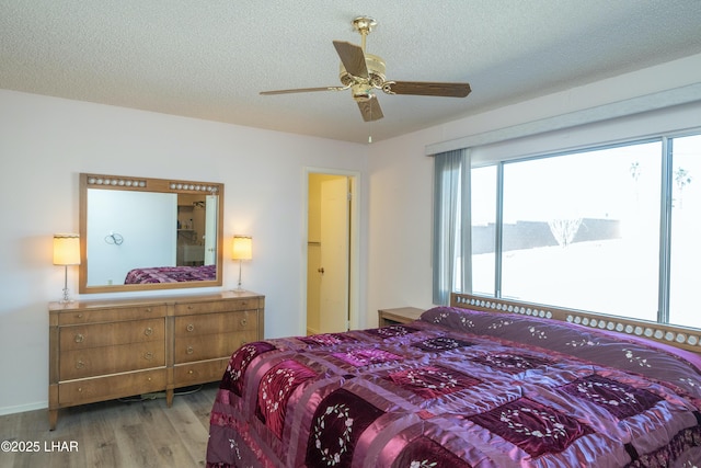 bedroom with a textured ceiling, ceiling fan, and wood finished floors