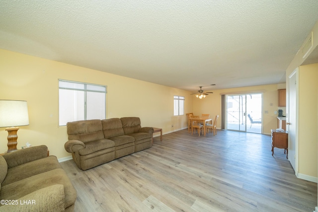 living room with light wood-style flooring, baseboards, and a textured ceiling