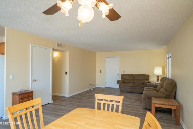 dining space with ceiling fan, a textured ceiling, wood finished floors, and visible vents