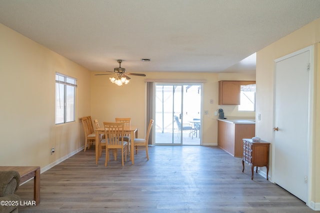 dining area with baseboards, light wood-type flooring, visible vents, and a healthy amount of sunlight