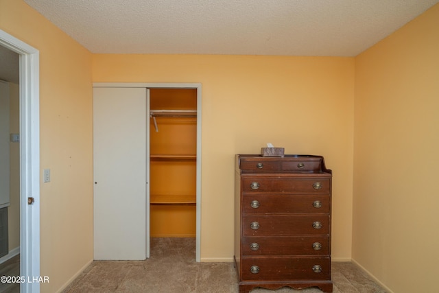 unfurnished bedroom with a closet, carpet flooring, a textured ceiling, and baseboards