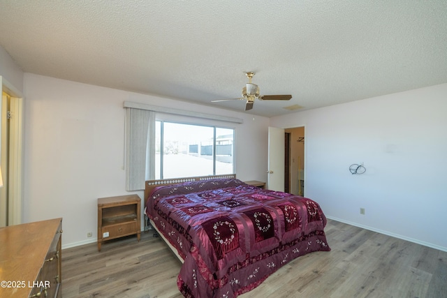 bedroom with a textured ceiling, wood finished floors, and baseboards