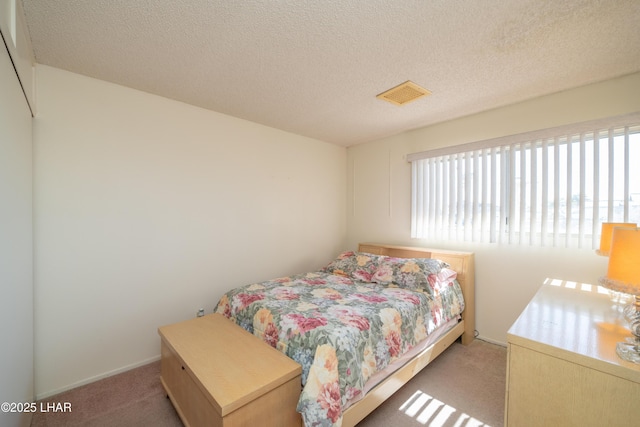 bedroom with light carpet, visible vents, and a textured ceiling