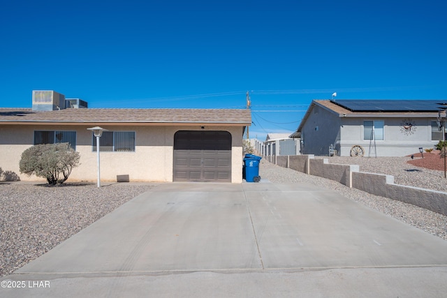 view of property exterior featuring an attached garage, central air condition unit, a shingled roof, driveway, and stucco siding