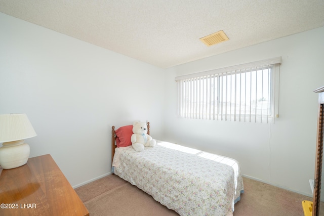 carpeted bedroom featuring visible vents, a textured ceiling, and baseboards