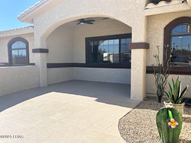 view of exterior entry featuring a patio area and ceiling fan