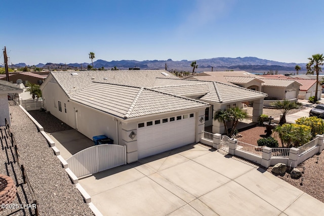 ranch-style home with an attached garage, a tile roof, a gate, and a mountain view