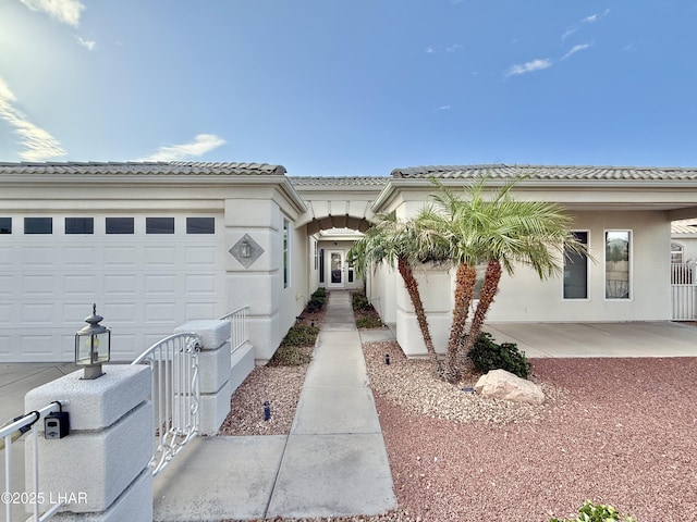 view of front of property with stucco siding, a tile roof, fence private yard, and a garage