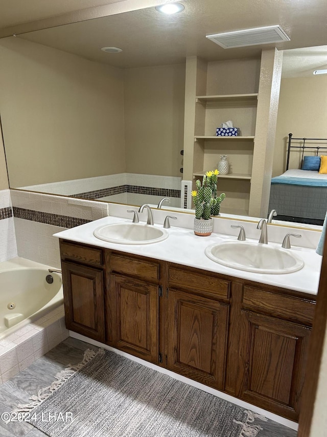 bathroom with vanity and a relaxing tiled tub